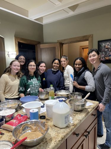A small group of medical students standing in a kitchen surrounded by baking supplies