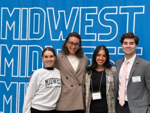 Four medical students standing in front of a MIDWEST sign